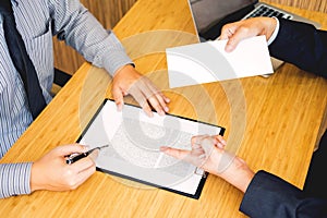 Hand of a businessman hands over a resignation letter final remuneration to executive boss on a wooden table to his boss Change of