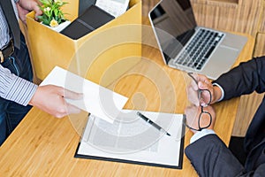 Hand of a businessman hands over a resignation letter final remuneration to executive boss on a wooden table to his boss Change of