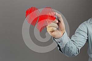 Hand of a businessman holding a pen point to red heart shape log