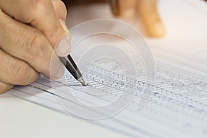 Hand Businessman holding pen for writing checking reports papers over application form