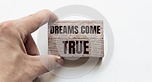 Hand of a businessman holding wooden blocks. Conceptual image. Text DREAM COME TRUE concept business succeed