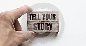 Hand of a businessman holding wooden blocks. Conceptual image. Text TELL YOU STORY concept business succeed