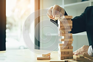 Hand of businessman playing wood blocks stacks game with planning strategy of project management