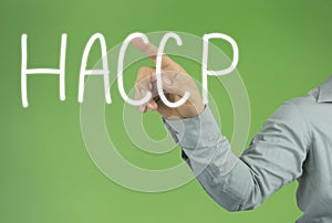 Hand of the businessman pointing to the HACCP text on green back
