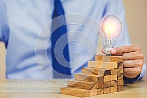 Hand of businessman pulling out or placing wood block on the tower, plan and strategy in business