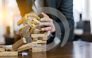 Hand of businessman pulling wood block fail on building