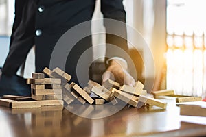 Hand of businessman pulling wood block fail on building