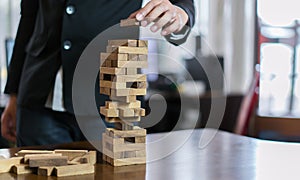 Hand of businessman pulling wooden block before fail on building