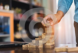 Hand of businessman pulling wooden block before fail on building