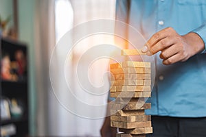 Hand of businessman pulling wooden block before fail on building