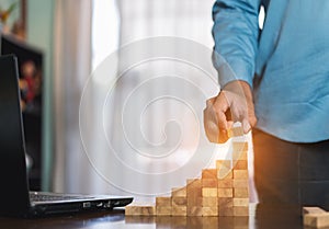 Hand of businessman pulling wooden block before fail on building tower