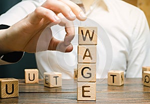 Hand of a businessman removes wooden blocks with the word Wage. Salary reduction concept. Wages cuts. The concept of limited photo