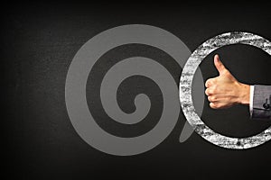 Hand of a businessman showing thumbs up on blackboard background