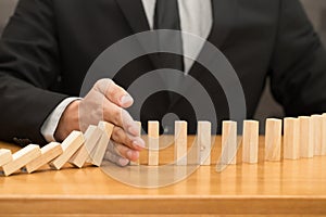 Hand of businessman stopping the domino effect. Risk control con