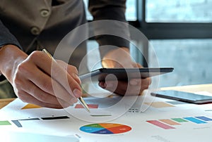 Hand businessman work on tablet in offices with graphs on the desk