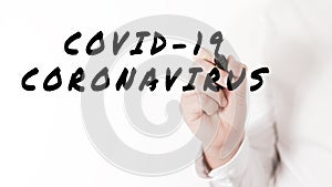 Hand of a businessman writing a word corona virus covid-19 in a conceptual image of corona virus outbreak