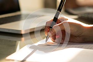 Hand of businesswoman writing on paper in office. Writing notes and planning her schedule