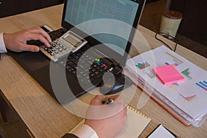 Hand with calculator. Finance and accounting business. Young Businessman Calculating Finance Bills In Office