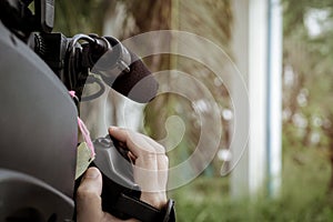 Hand of cameraman using camcorder shooting a video at the park.