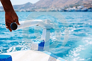 Hand of captain is controlling rudder engine on a wooden boat in the sea near island Crete. The concept of reliable and
