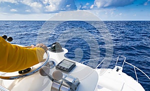 Hand of captain on steering wheel of motor boat in the blue ocean.