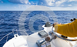 Hand of captain on steering wheel of motor boat in the blue ocean during the fishery day. Success fishing concept. Ocean yacht.