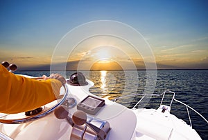 Hand of captain on steering wheel of motor boat in the blue ocean during the fishery day. Success fishing concept. Ocean yacht