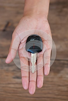 Hand with a car key on wood background