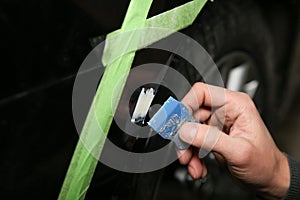 Hand of car service worker spackles a small dent on the bumper of the car