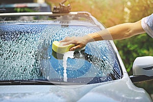 Hand car wash - washing windshield with sponge photo