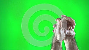 hand care on a green background chromakey man spreading white cream on his hands hairy male hands on the right side of