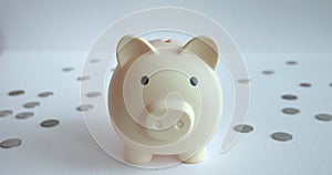 hand carefully places coin into piggy bank white table, amidst other coins, savings. symbol financial prudence