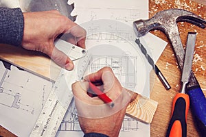 Hand of a carpenter taking measurement of a wooden plank