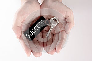 The hand carry the silver key with the label of success wording. Key to success concept isolated in white background