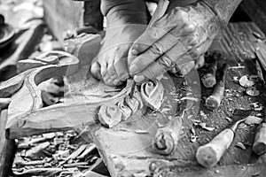 Hand of carver carving wood in black and white color tone