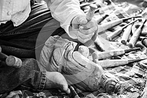 Hand of carver carving wood in black and white color tone