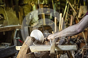 Hand carving a wooden bowl with a foot powered wood lathe, in an old carpenter`s workshop with carpenter`s wood tools