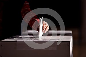 Hand casting a vote into the ballot box photo