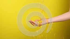 Hand catches corn porridge on a yellow background