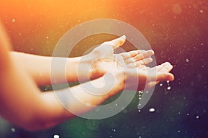 Hand catching rain drops on blurred background. Woman hands praying for blessing from god on sunset. Empowerment, sacred