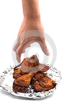 Hand catching roasted wing. delicious grill chicken on foil on isolated white background. Food and appetizer concept