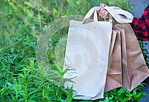 Hand of caucasian girl holding eco friendly white cloth (canvas fabric) bag and paper bags for organic shopping.