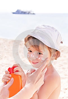 Hand of caucasian mother applying suncream to her