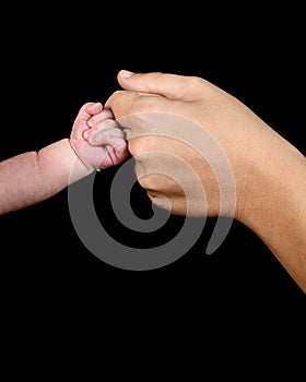 The hand of a caucasian newborn with a clenched fist bumps the knuckles against the mother`s fist.