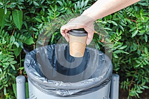 Hand of a caucasian woman trashing a cup of  coffee in a bin photo