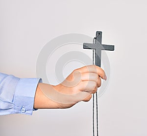 Hand of caucasian young catholic woman holding christian cross over isolated white background