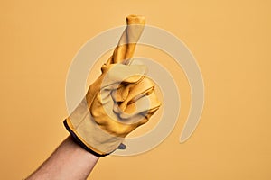 Hand of caucasian young man with gardener glove over isolated yellow background counting number one using index finger, showing
