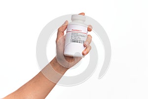 Hand of caucasian young man holding bottle of  pills over isolated white background