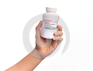 Hand of caucasian young man holding bottle of  pills over isolated white background