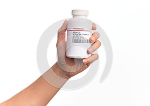 Hand of caucasian young man holding bottle of  pills over isolated white background